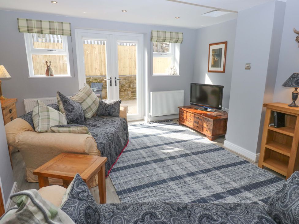 A living room with a sofa and a television at Milburn Cottage in Keighley
