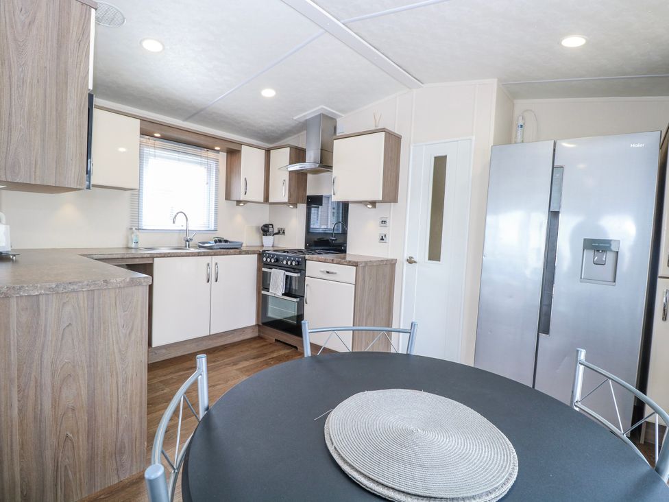 A kitchen with appliances and dining area at 59 Cliff Field in Lowestoft