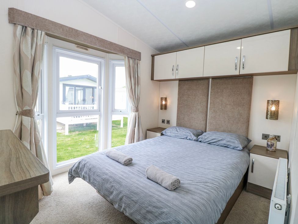 A bedroom with a bed and two windows at 59 Cliff Field in Lowestoft