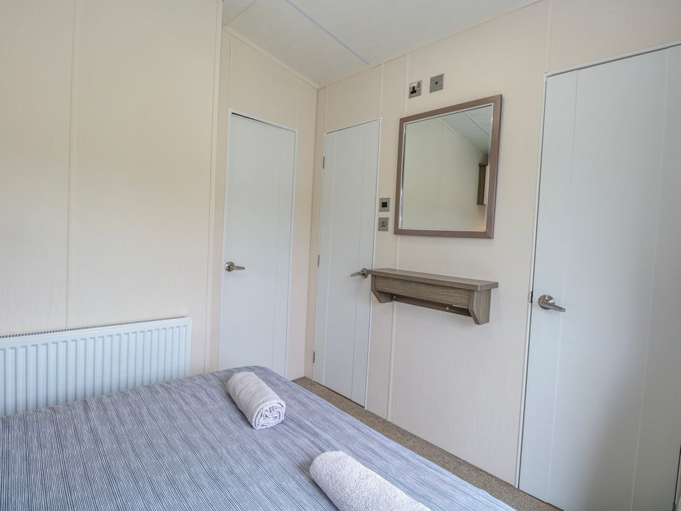 A bedroom with a bed and mirror at 59 Cliff Field in Lowestoft