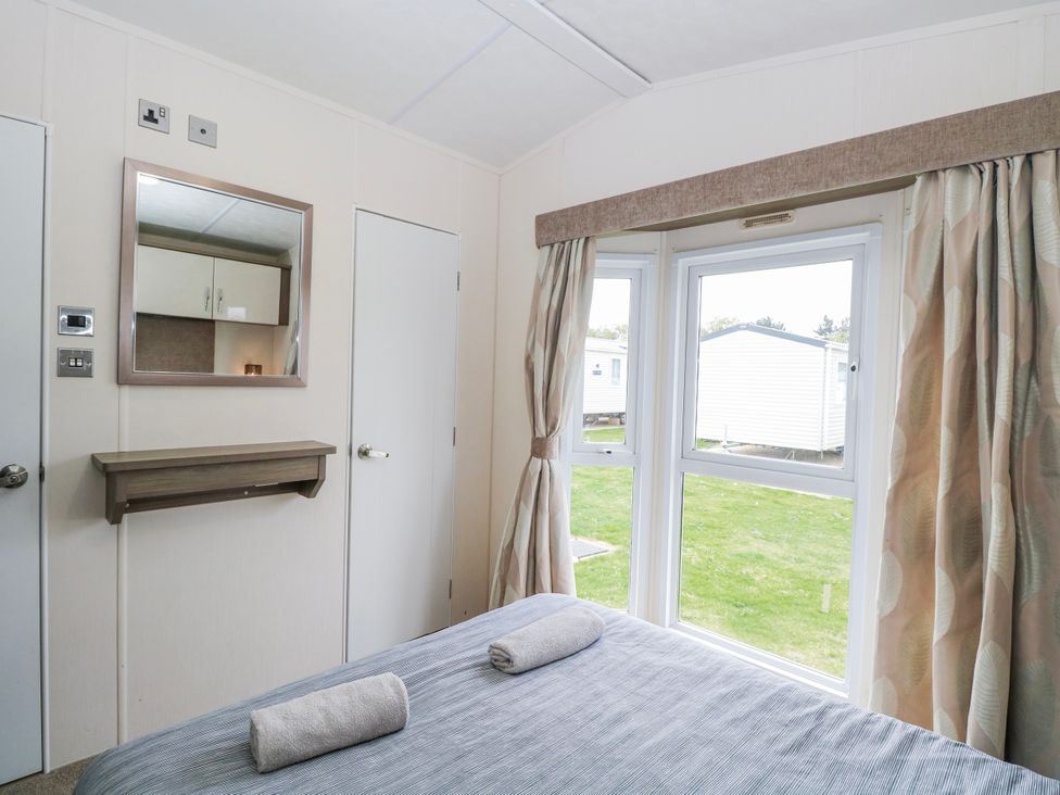 A bedroom with a bed and a mirror at 59 Cliff Field in Lowestoft