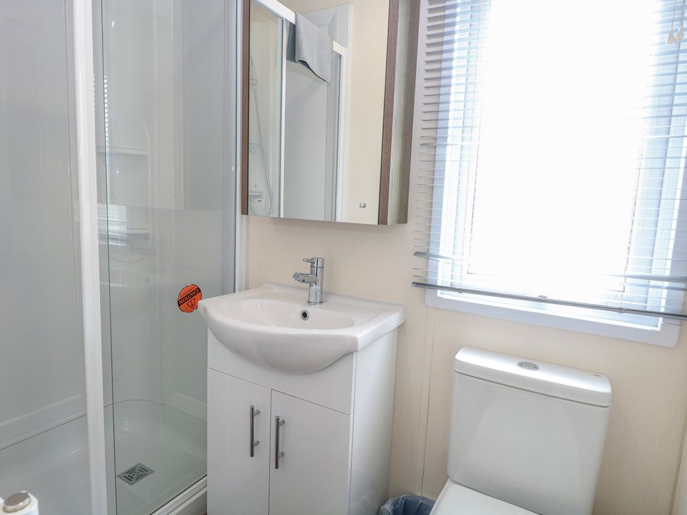 A bathroom with a shower, sink, cabinet and toilet at 59 Cliff Field in Lowestoft
