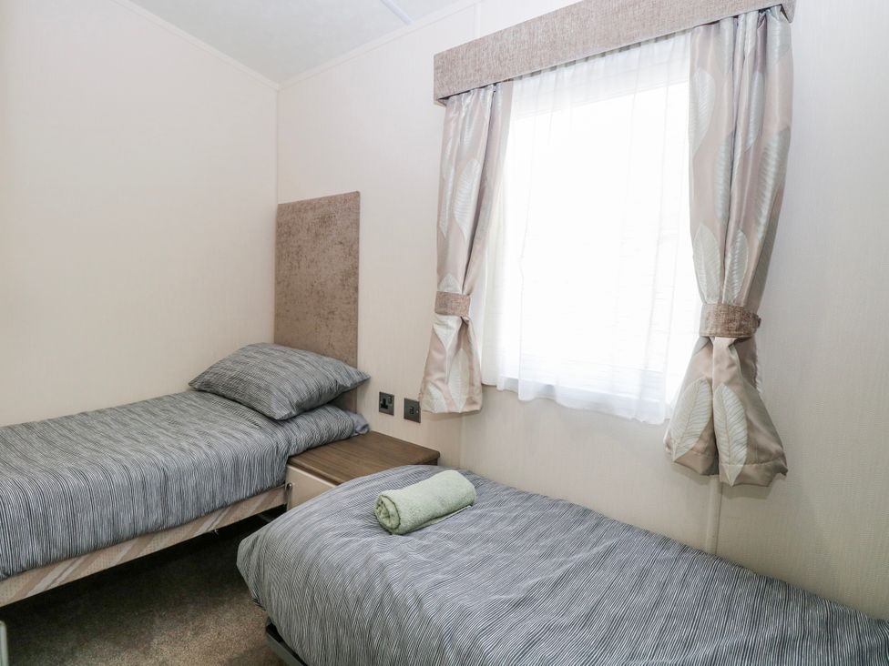 A bedroom with two single beds and a window at 59 Cliff Field, Lowestoft