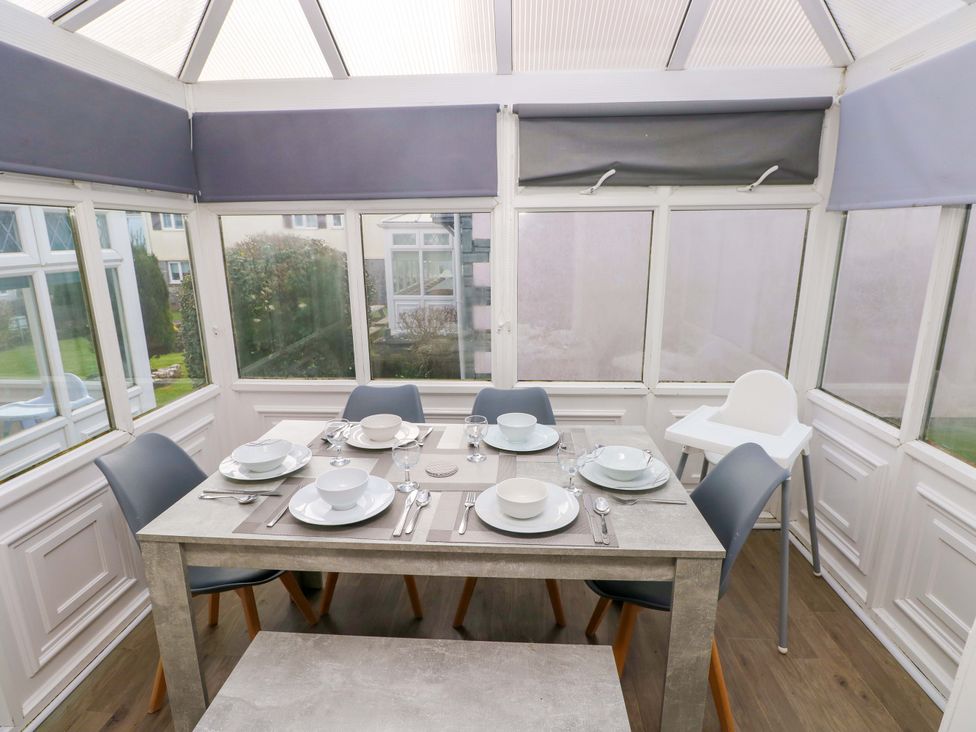 A dining area with a table and chairs in a conservatory at The Wool Pack in Tenby