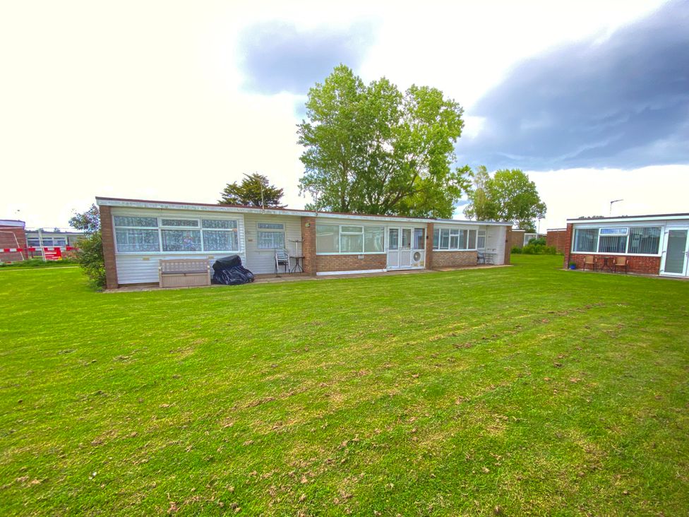 A bungalow with windows and grass area at Chalet 62 California, Norfolk