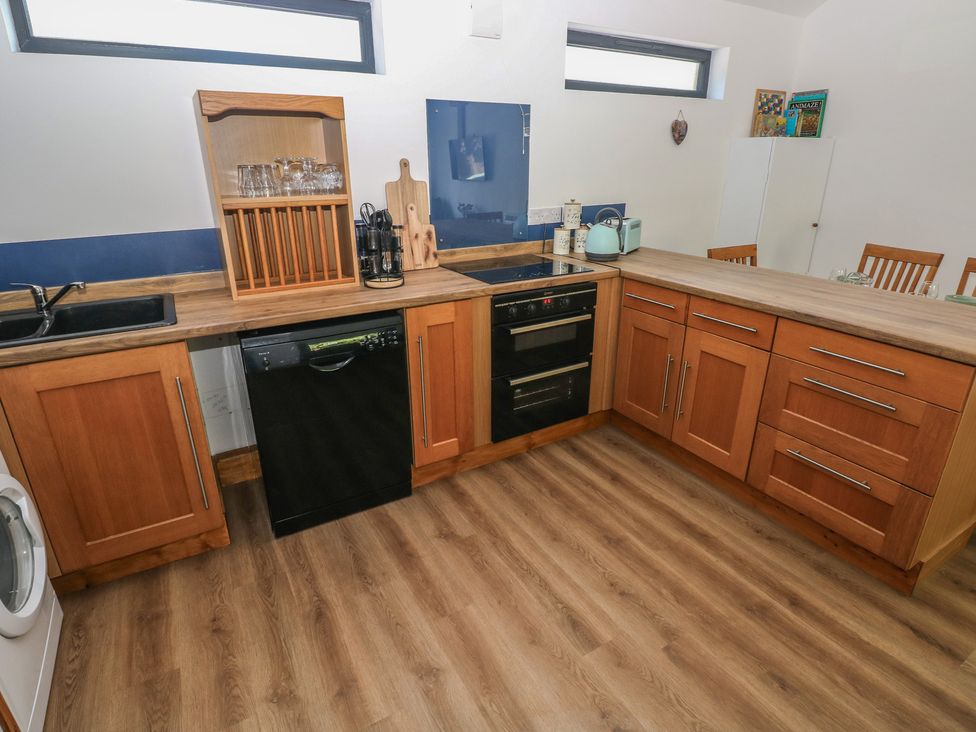 A kitchen with wooden cabinets and appliances at Brookview Goldfinch in Haverfordwest