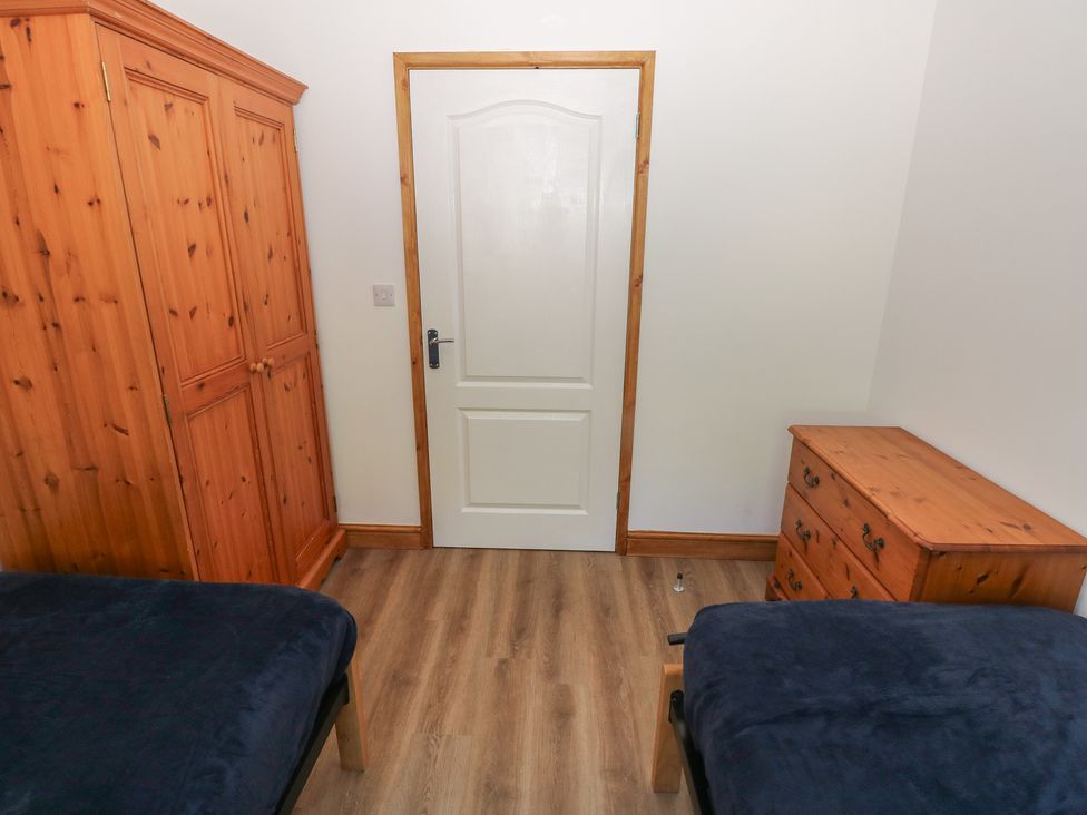 A bedroom with a wardrobe, chest of drawers, and two beds at Brookview Goldfinch Haverfordwest