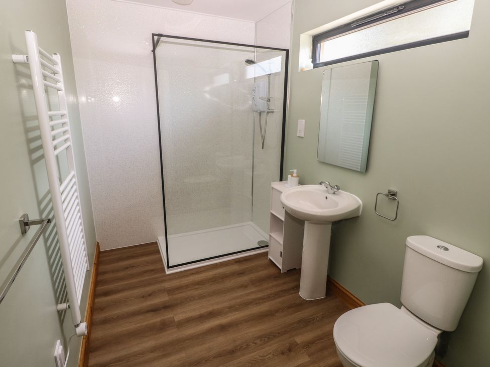 A bathroom with a shower, wash basin, toilet, and towel rail at Brookview Goldfinch in Haverfordwest