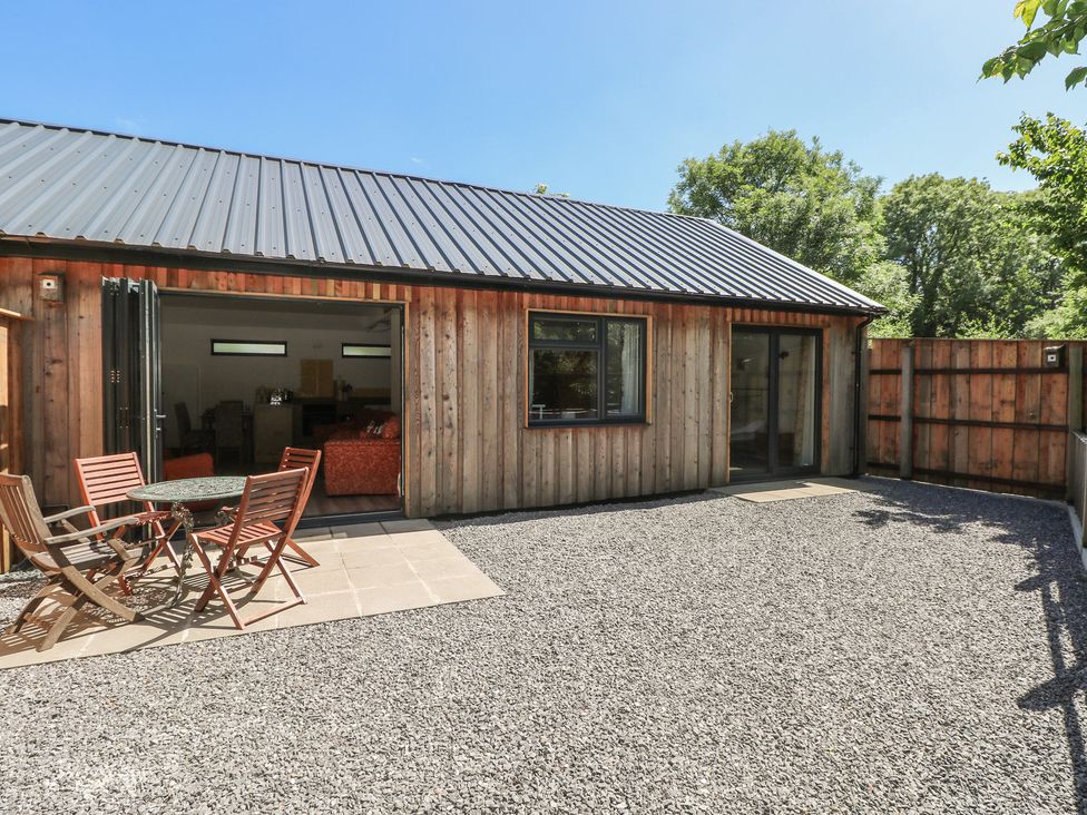 An outdoor area with a wooden building and a table with chairs at Brookview Goldfinch in Haverfordwest