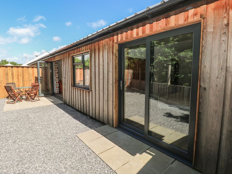 A wooden building with a sliding door and outdoor seating at Brookview Goldfinch Haverfordwest