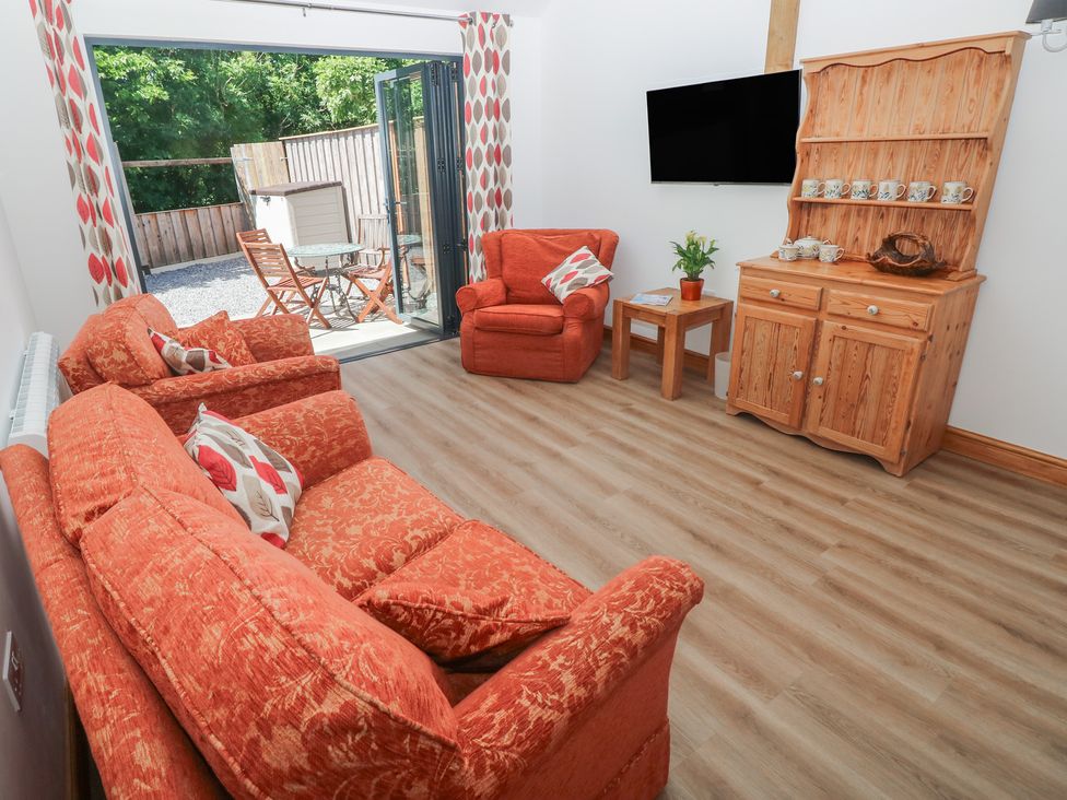 A living room with orange furniture and a television at Brookview Goldfinch in Haverfordwest