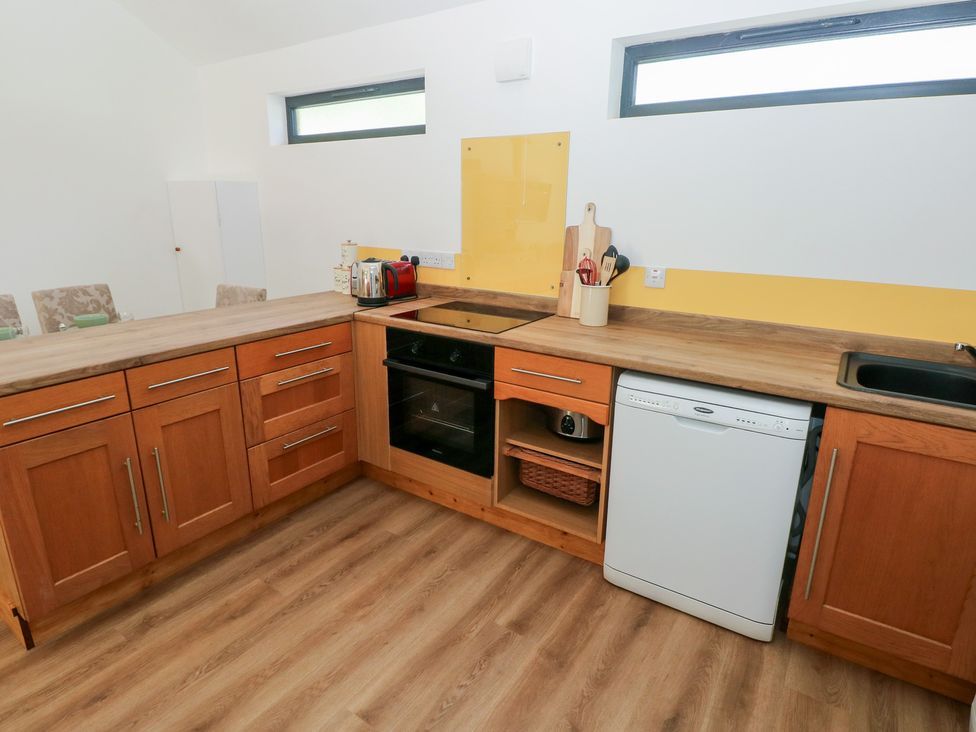 A kitchen with wooden cabinets and appliances at Brookview Goldfinch in Haverfordwest