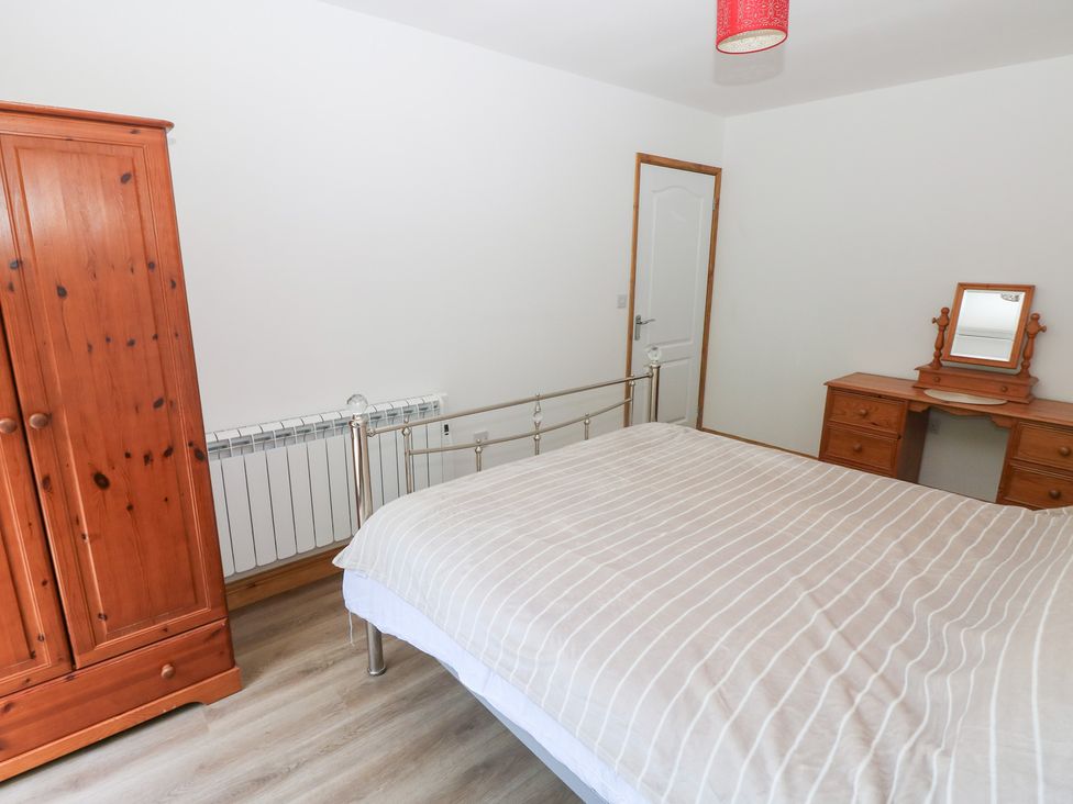 A bedroom with a bed, wardrobe, desk and mirror at Brookview Goldfinch in Haverfordwest