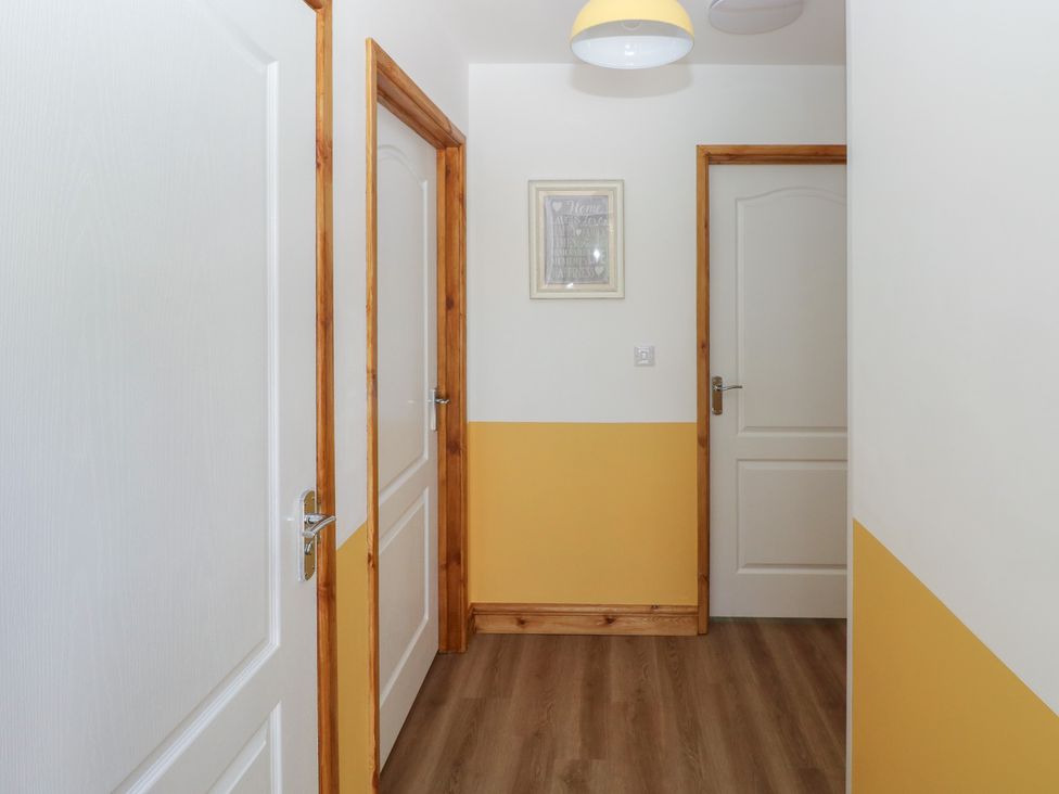 A hallway with doors and a picture at Brookview Goldfinch in Haverfordwest