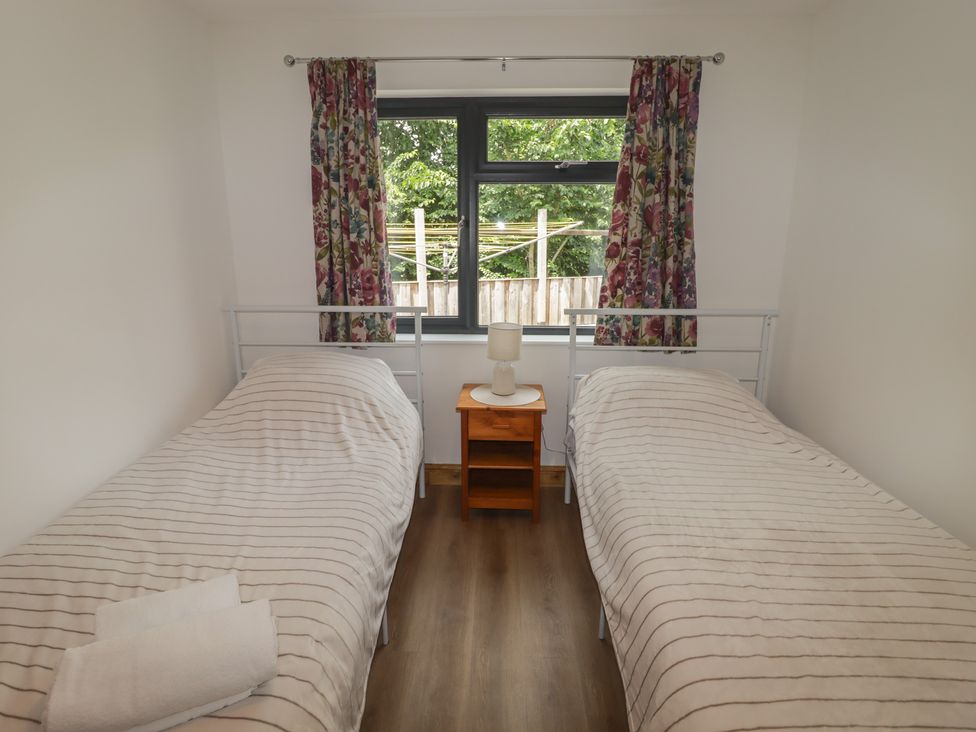 A bedroom with two beds and a nightstand at Brookview Goldfinch in Haverfordwest