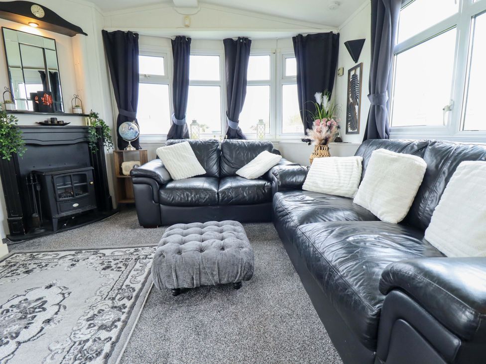 A living room with a black sofa and footstool at Towervans Z11 in Mablethorpe