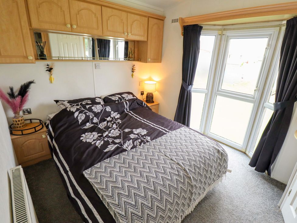 A bedroom with a bed, bedside table, and windows at Towervans Z11 in Mablethorpe