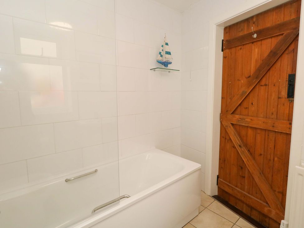 A bathroom with a bathtub and a wooden door at NO 10 Fortuneswell