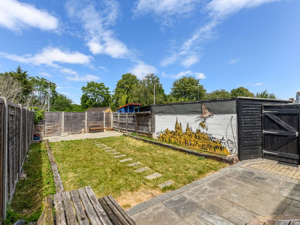 A garden with a fence, grass, stone pathway, bench, and mural at Florence of Oxford, Oxford