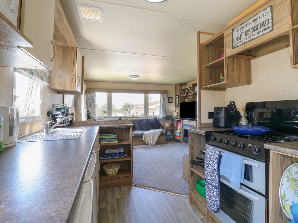 A kitchen with appliances and living area at Estuary View in Allhallows