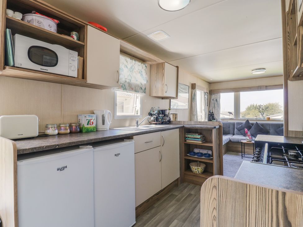 A kitchen with appliances and seating area at Estuary View in Allhallows