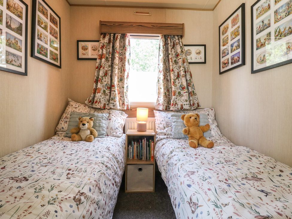 A bedroom with two beds and a bedside table at Estuary View in Allhallows