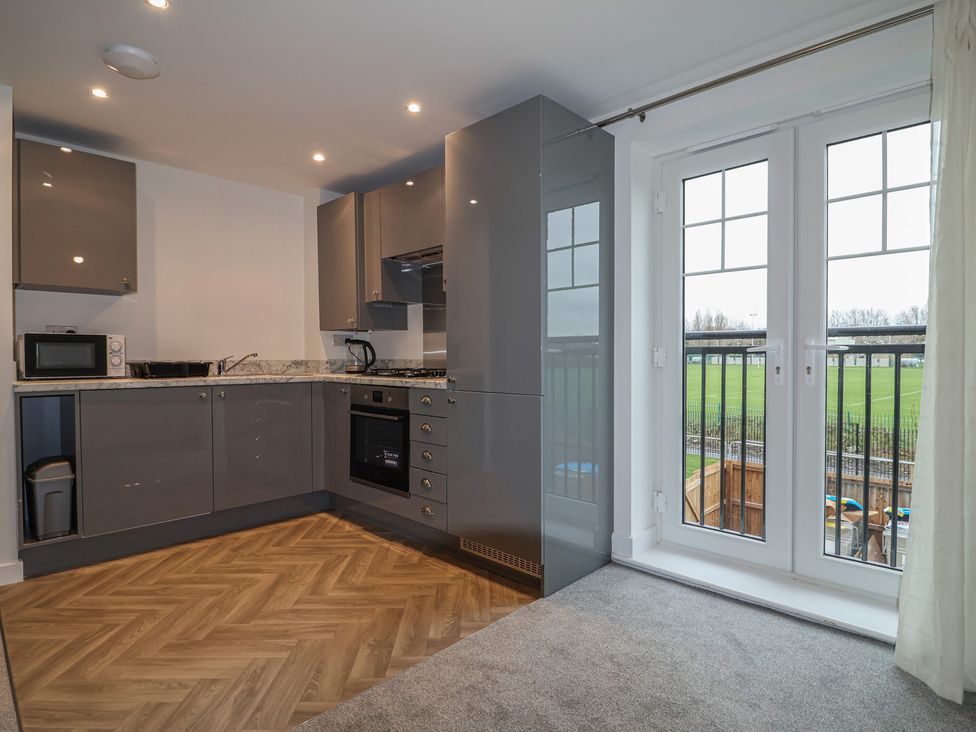 A kitchen with modern appliances and a balcony door at Apartment 7 at Anfield Liverpool