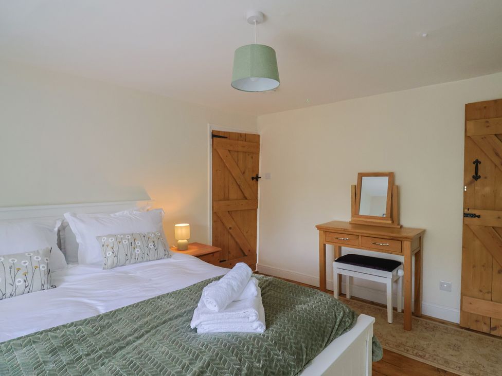A bedroom with a bed and a dressing table at Harbins Farm in Glanvilles Wootton Nr. Sherborne