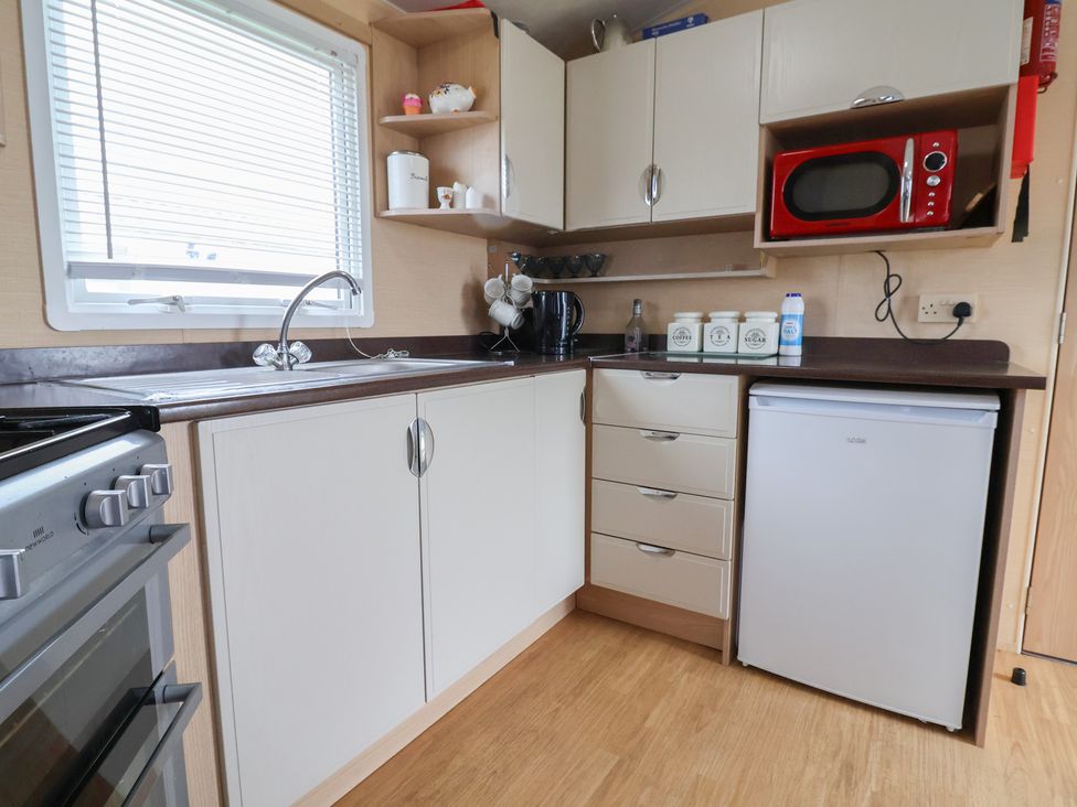 A kitchen with cabinets, sink, microwave, and countertop at Winchester - 244