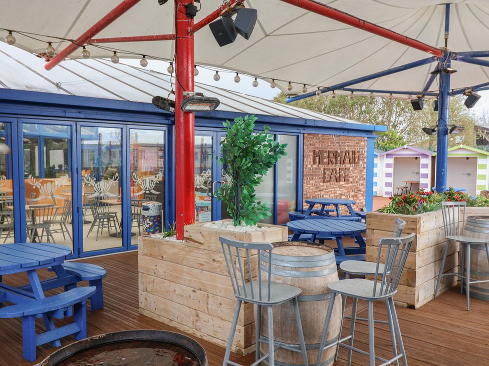An outdoor seating area with wooden barrels and seating at Mermaid Lane