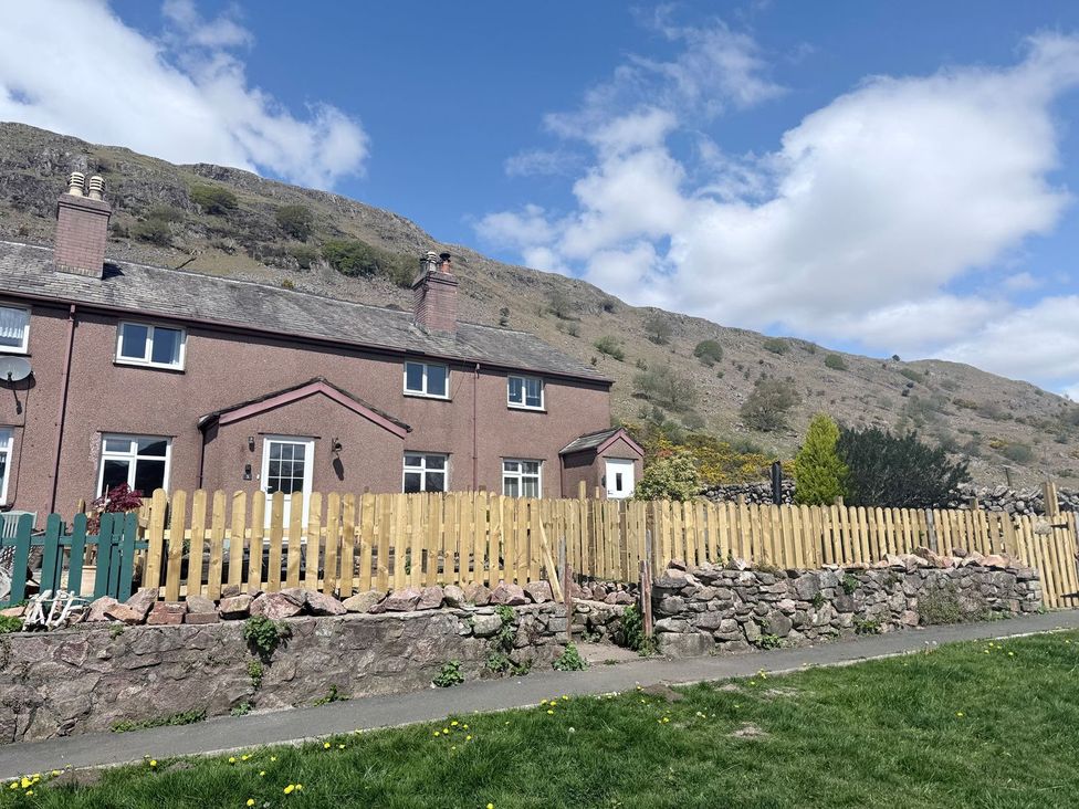 A house with a fence and mountain backdrop at Pandora in Holmrook