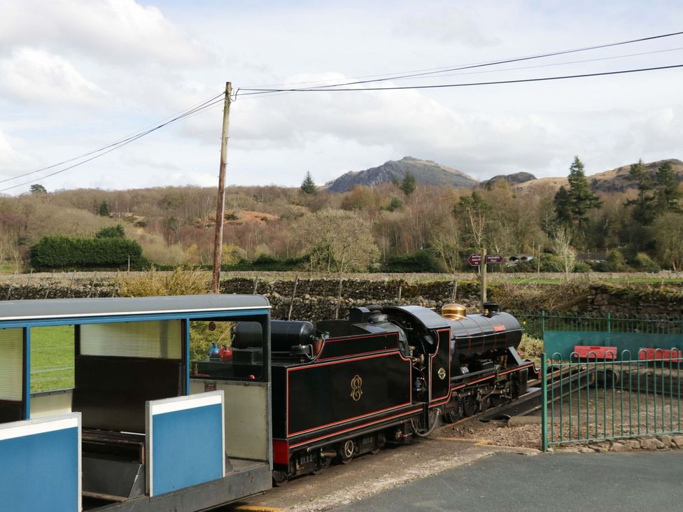 A steam train and carriage at a station with mountains in the background at Pandora in Holmrook
