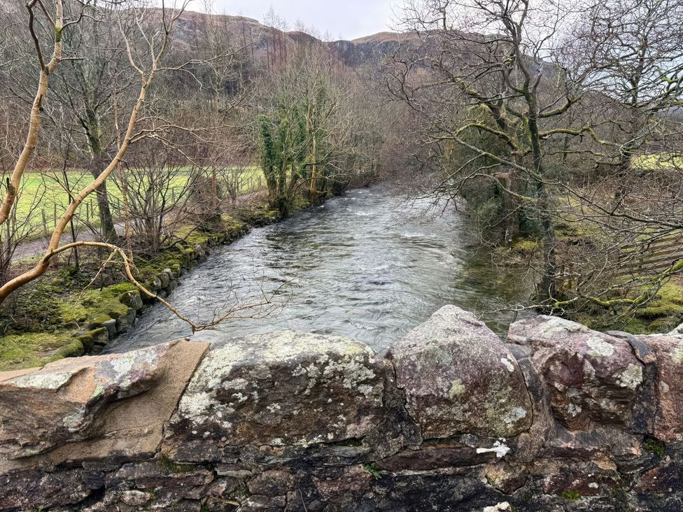 A river surrounded by trees and a stone wall at Pandora in Holmrook