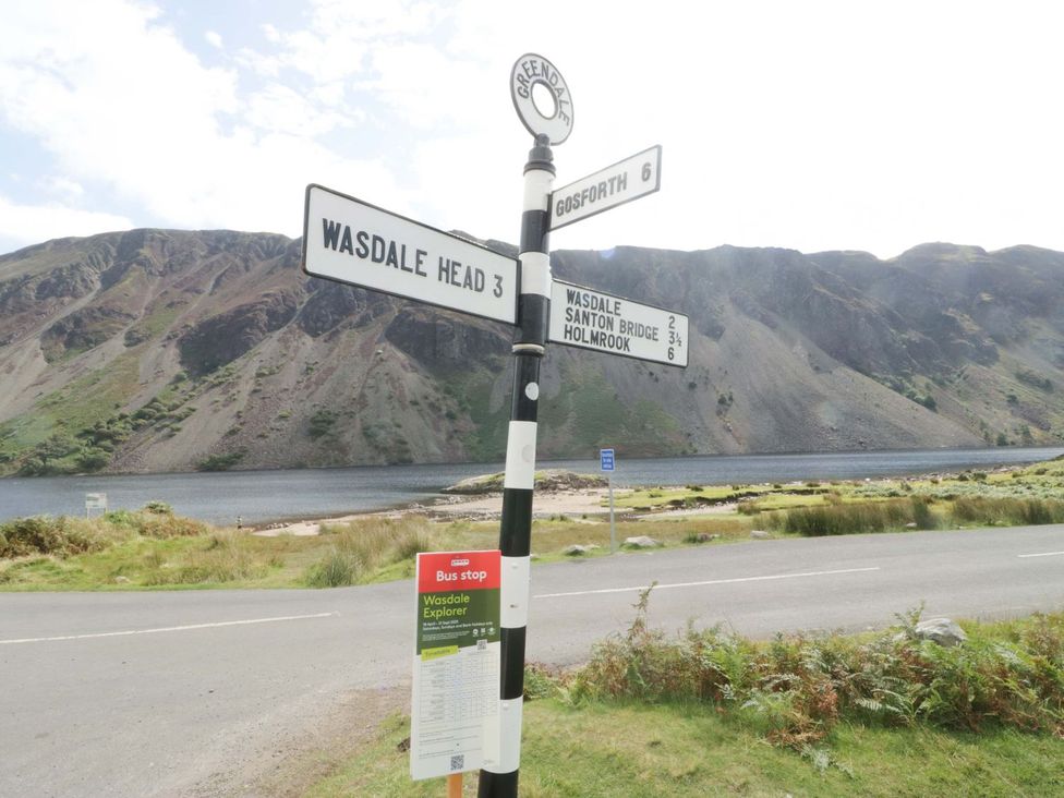 A signpost with distance markers near a lake and mountains at Pandora Holmrook