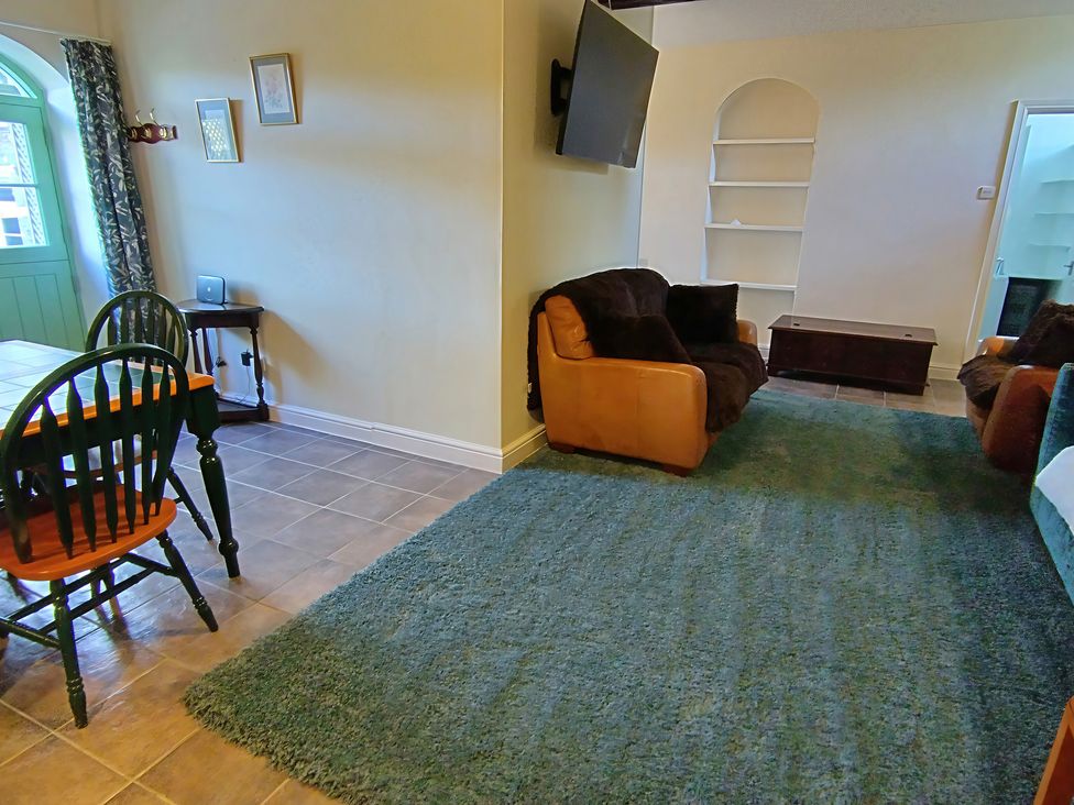 A living room with a sofa and dining table at Linhay Barn in Saltash