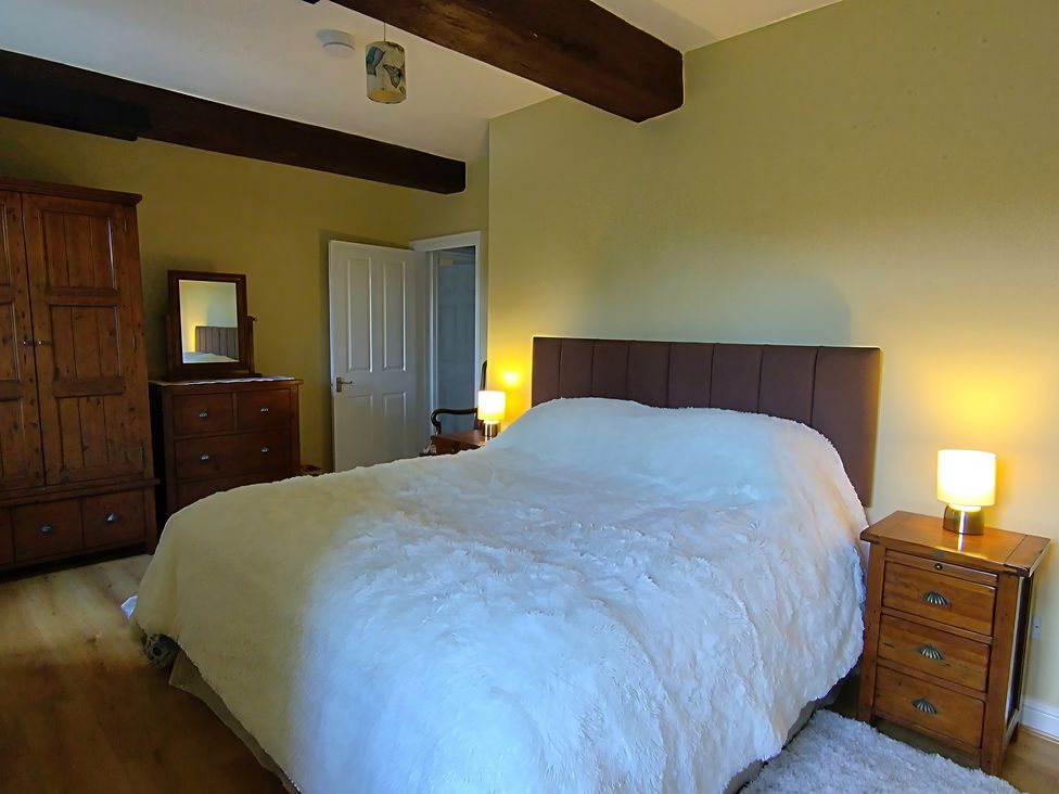 A bedroom with a bed and wooden furniture at Linhay Barn Saltash