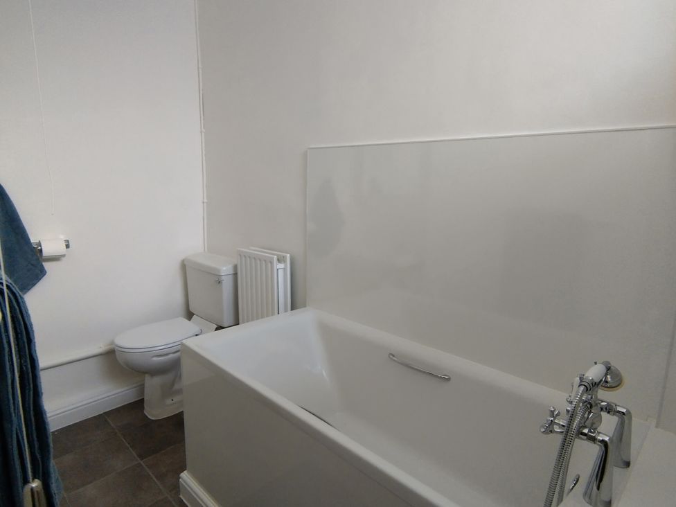 A bathroom with a bathtub and toilet at Linhay Barn Saltash