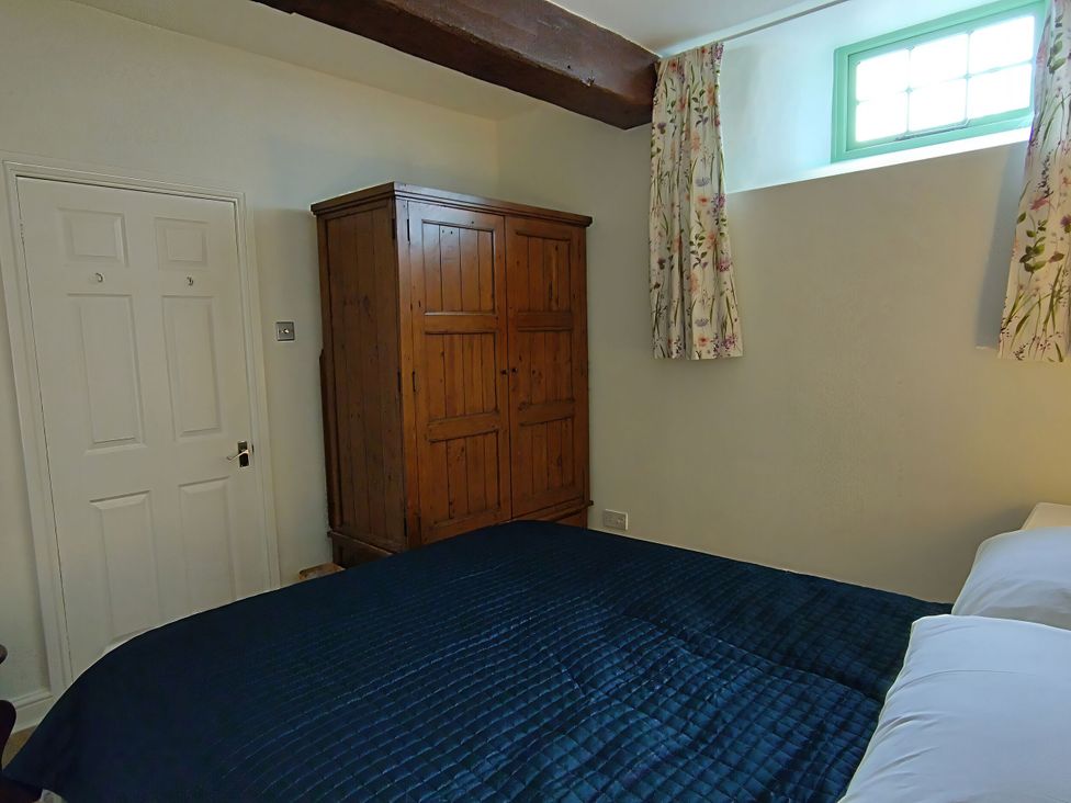 A bedroom with a bed and wardrobe at Linhay Barn Callington