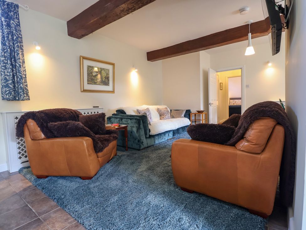 A living room with a sofa and armchairs at Linhay Barn in Callington