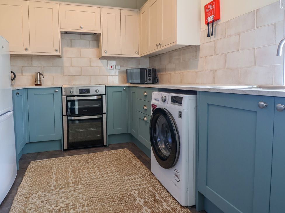 A kitchen with appliances including an oven and washing machine at Linhay Barn Callington