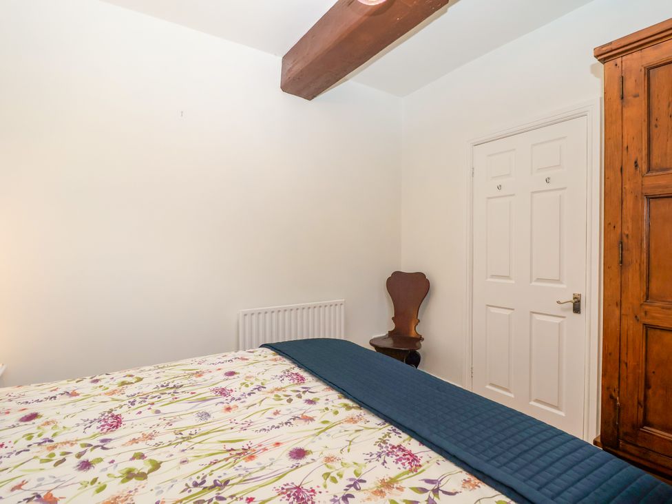 A bedroom with a bed, wardrobe, and chair at Linhay Barn in Callington