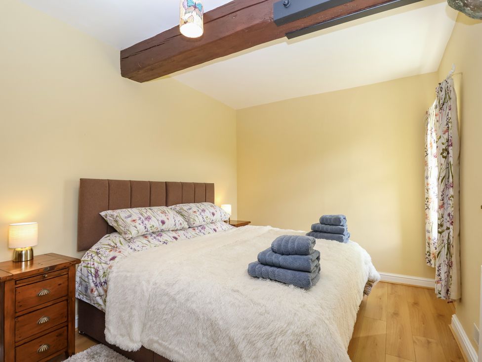 A bedroom with a bed, towels, and a bedside table at Linhay Barn in Callington