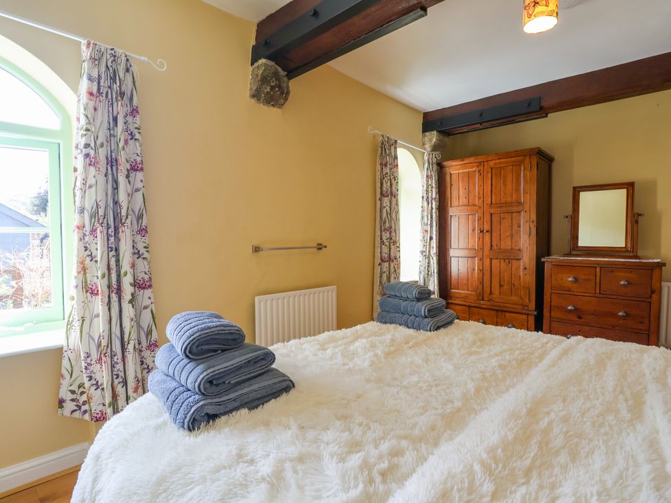 A bedroom with a bed and towels arranged at Linhay Barn Callington