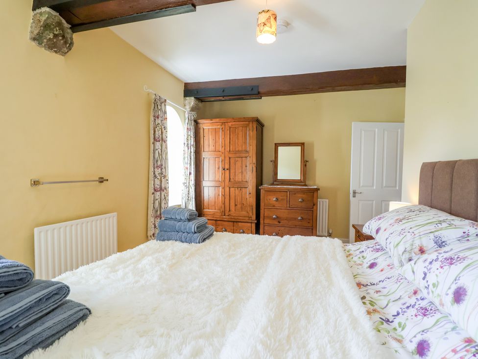 A bedroom with a bed and wooden furniture at Linhay Barn in Callington