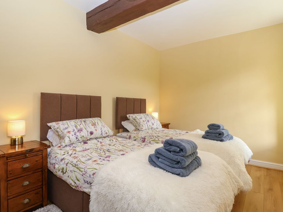 A bedroom with twin beds and towels at Linhay Barn in Callington