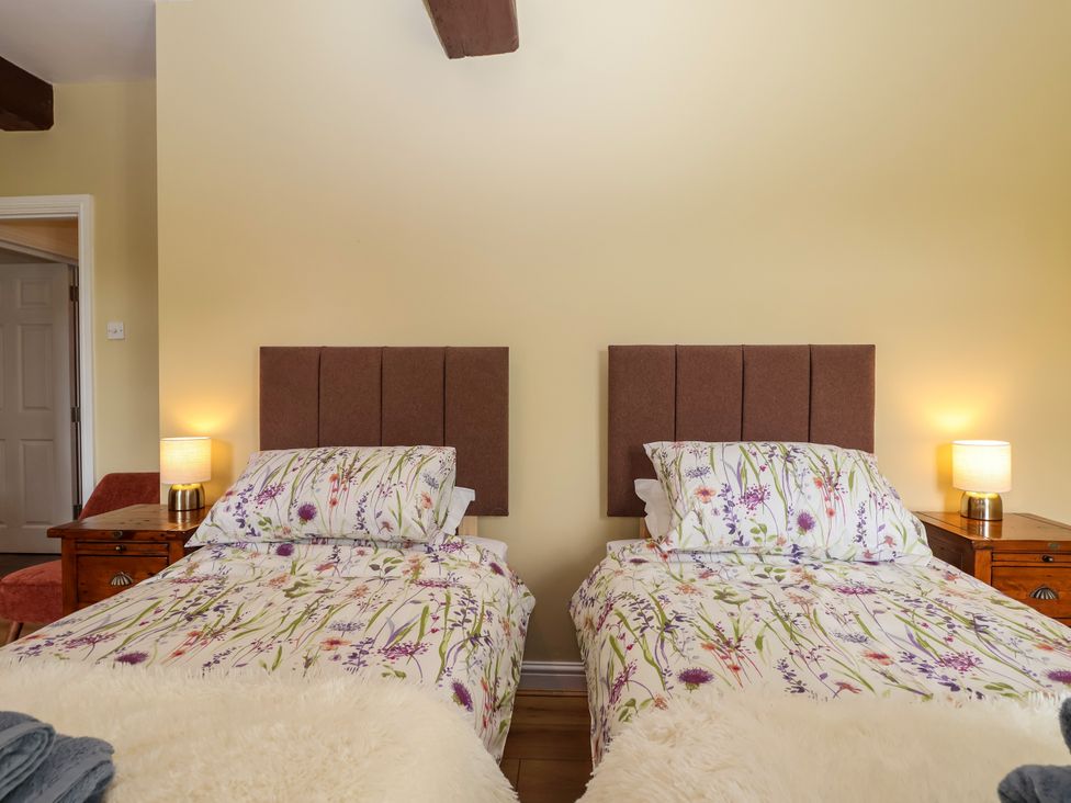 A bedroom with two beds and nightstands at Linhay Barn, Callington