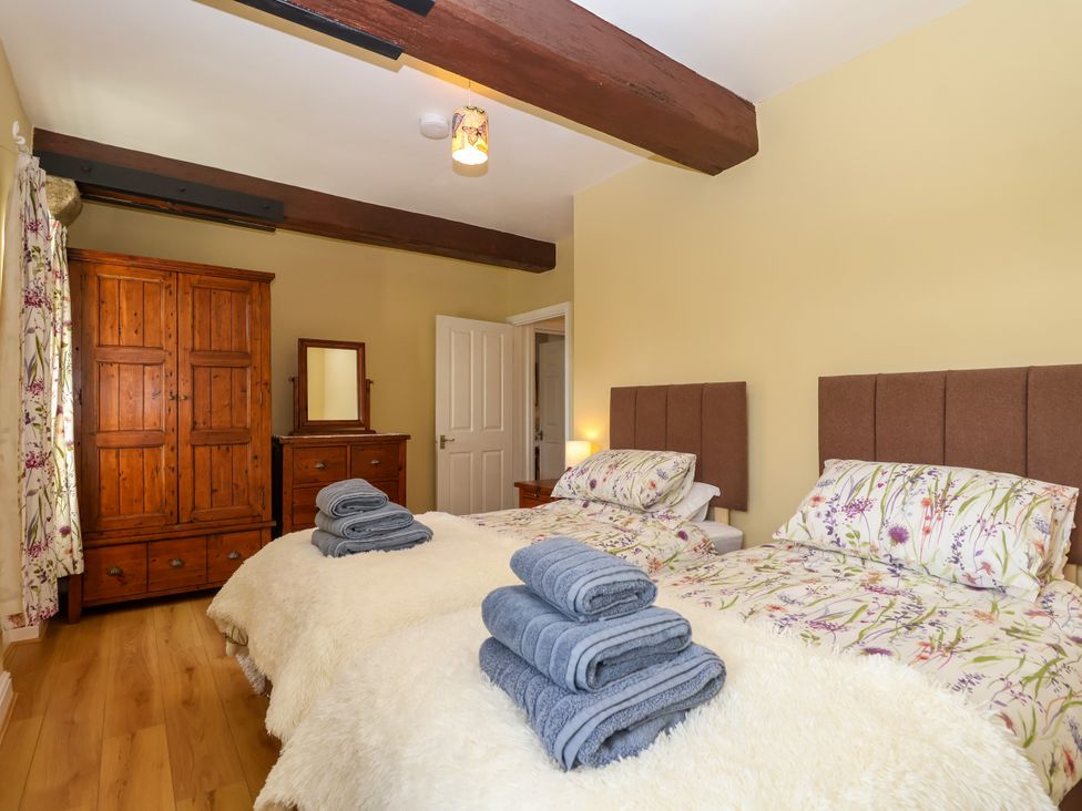 A bedroom with two beds and a wardrobe at Linhay Barn in Callington