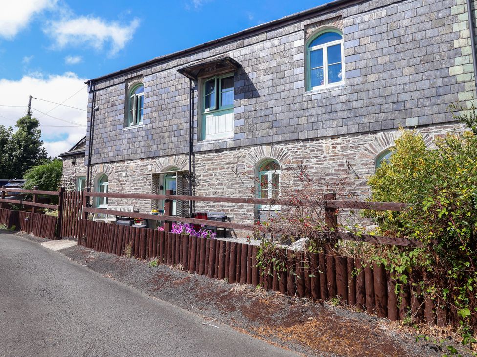 A stone building with windows and a wooden fence at Linhay Barn Callington