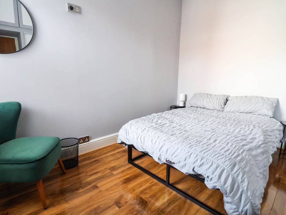 A bedroom with a bed and armchair at Seaside Home in New Brighton
