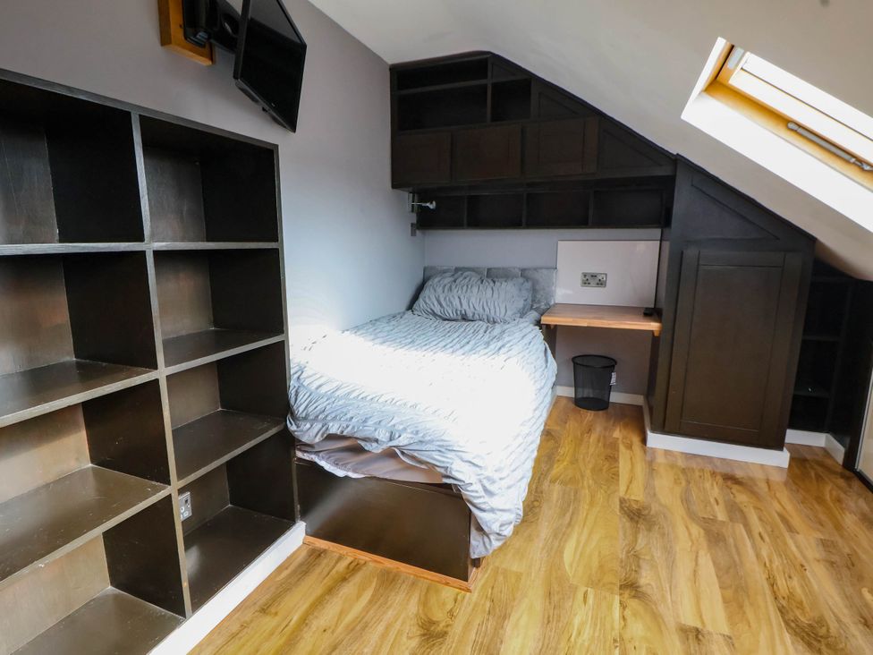 A bedroom with a bed and shelf unit at Seaside Home in New Brighton